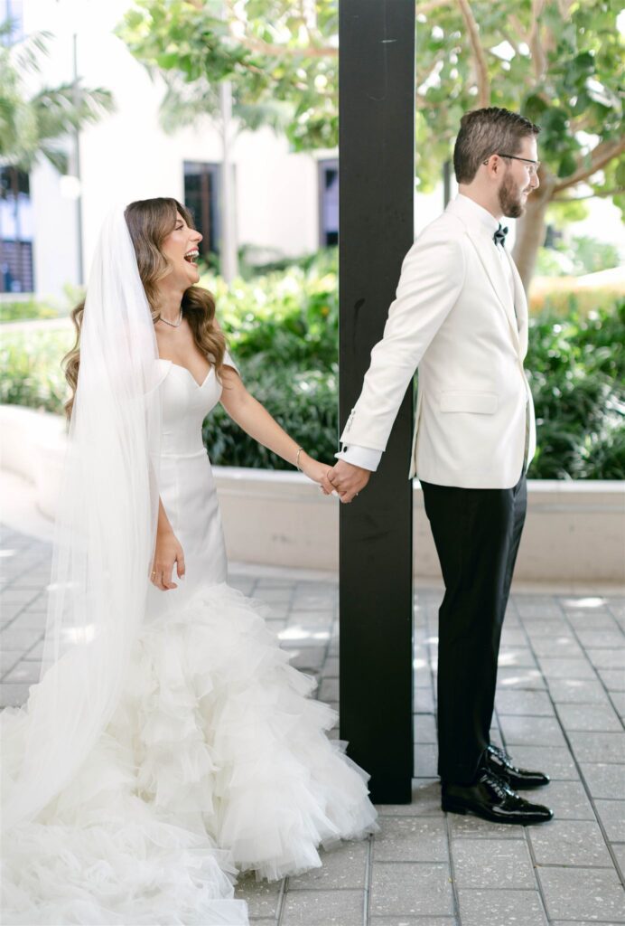 Bride and groom holding hands around a column for their first touch and private prayer