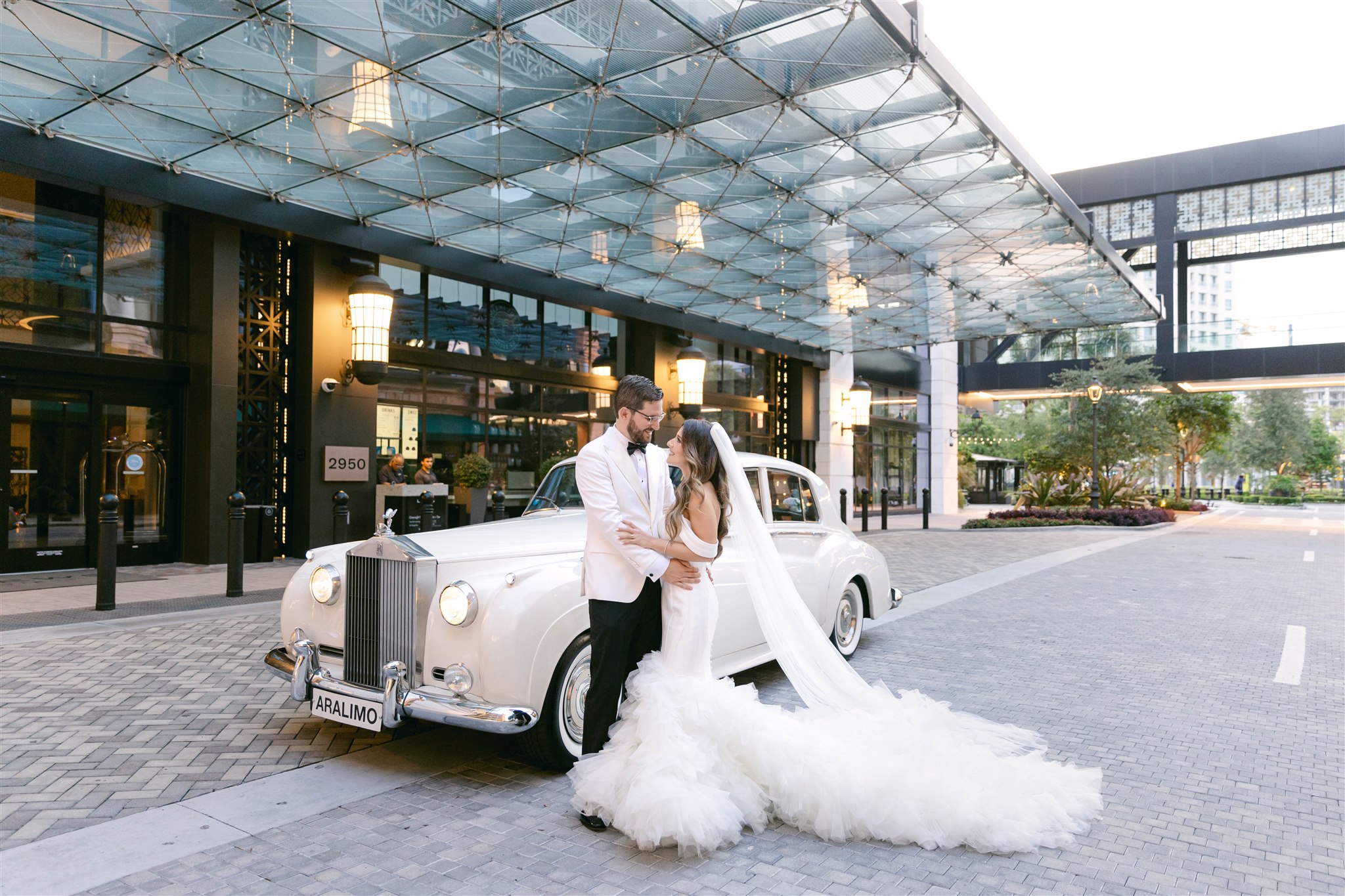 Bride and groom with the white Rolls-Royce outside Loews Coral Gables