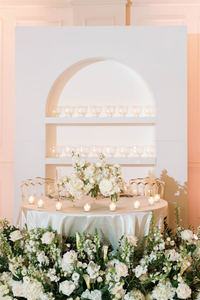 Sweetheart table with an arched backdrop and white florals