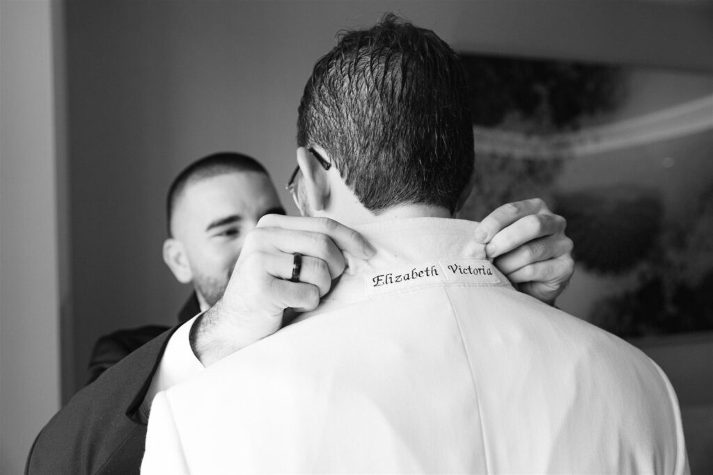 Groomsman helping the groom with his collar