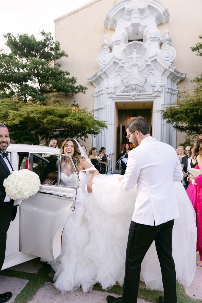 Newlyweds leaving the church for the white Rolls-Royce