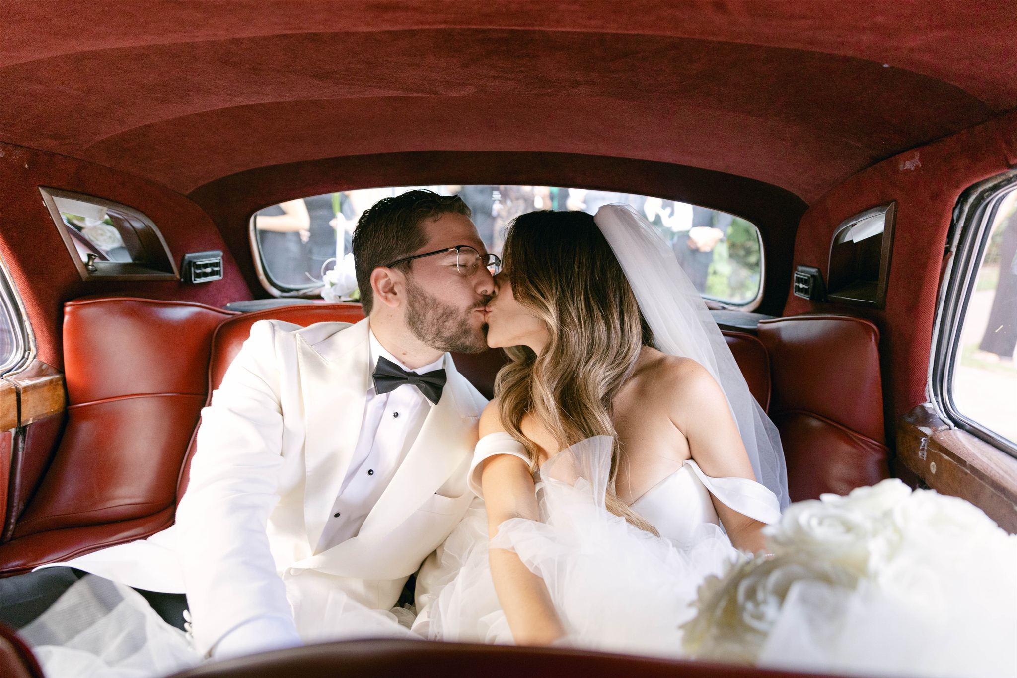 Bride and groom kissing in the back of the Rolls-Royce