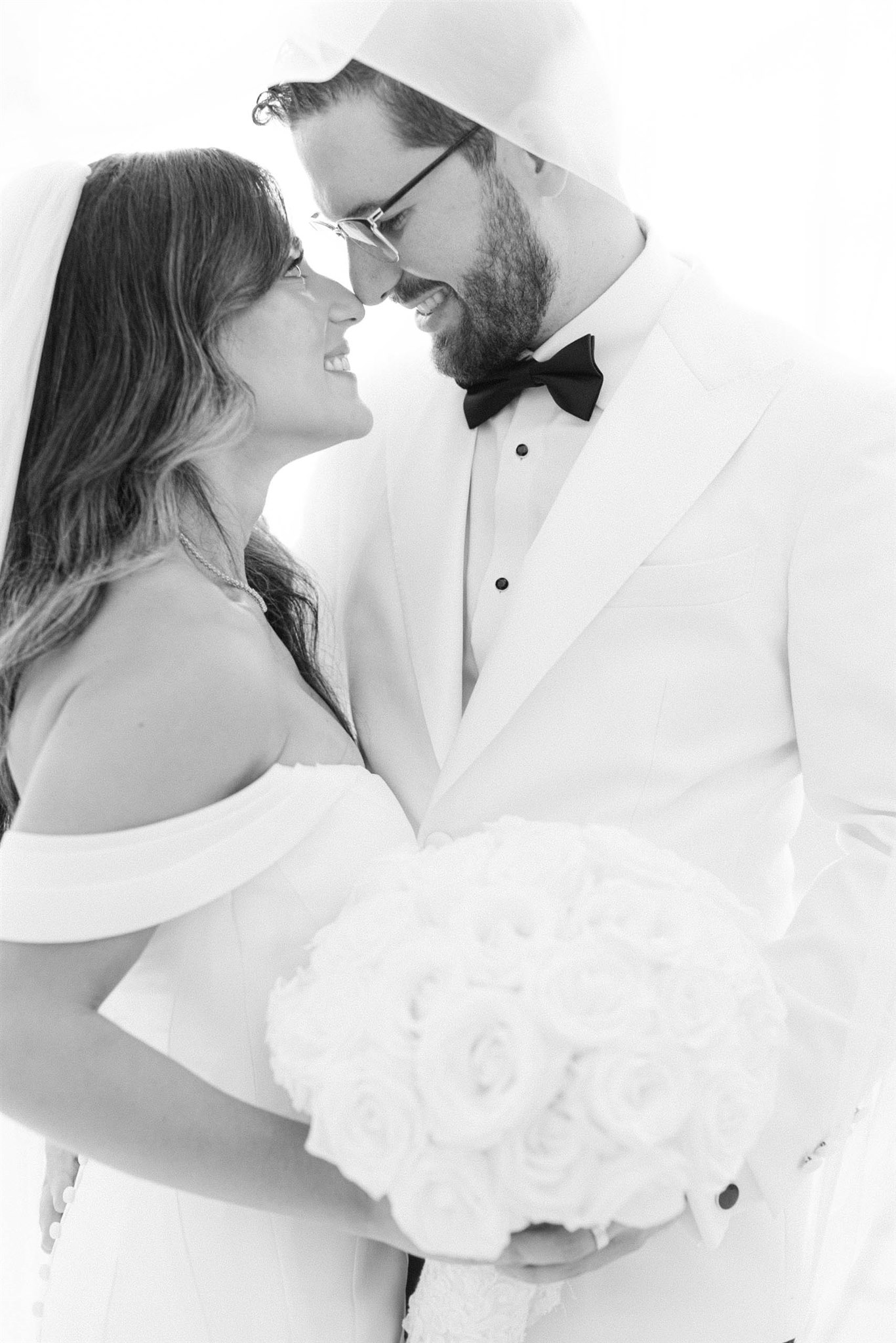 Bride and groom sharing a kiss with her white rose bouquet