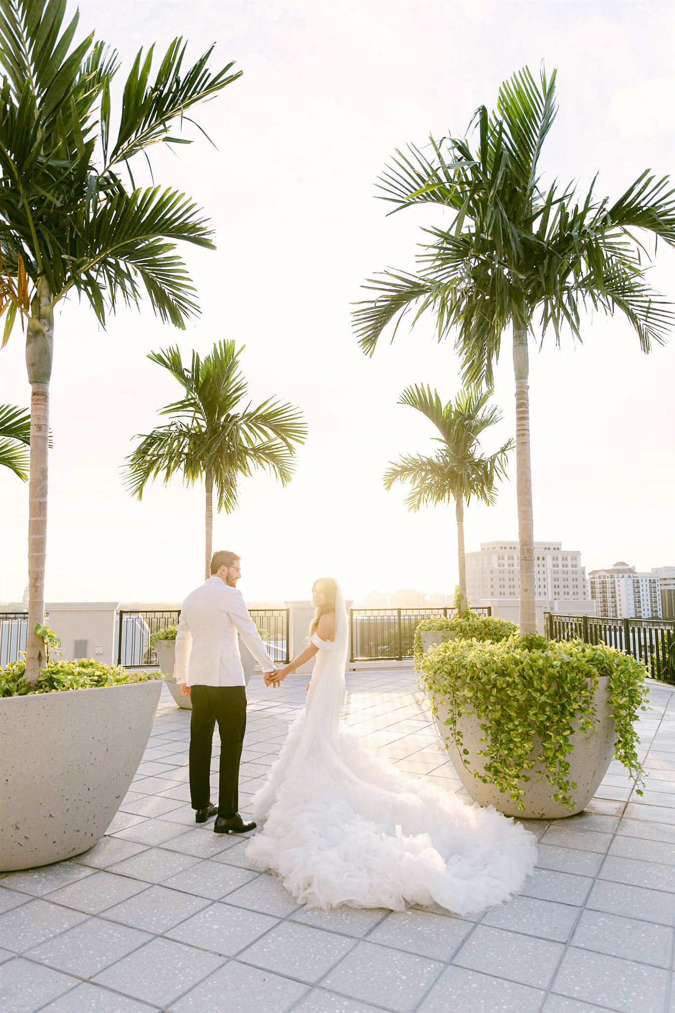 Bride and groom under palm trees at sunset at Loews Coral Gables