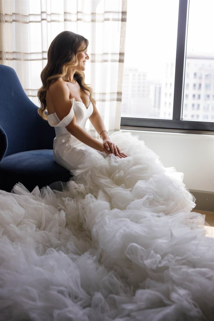 Bride seated by the window in her ruffled mermaid gown