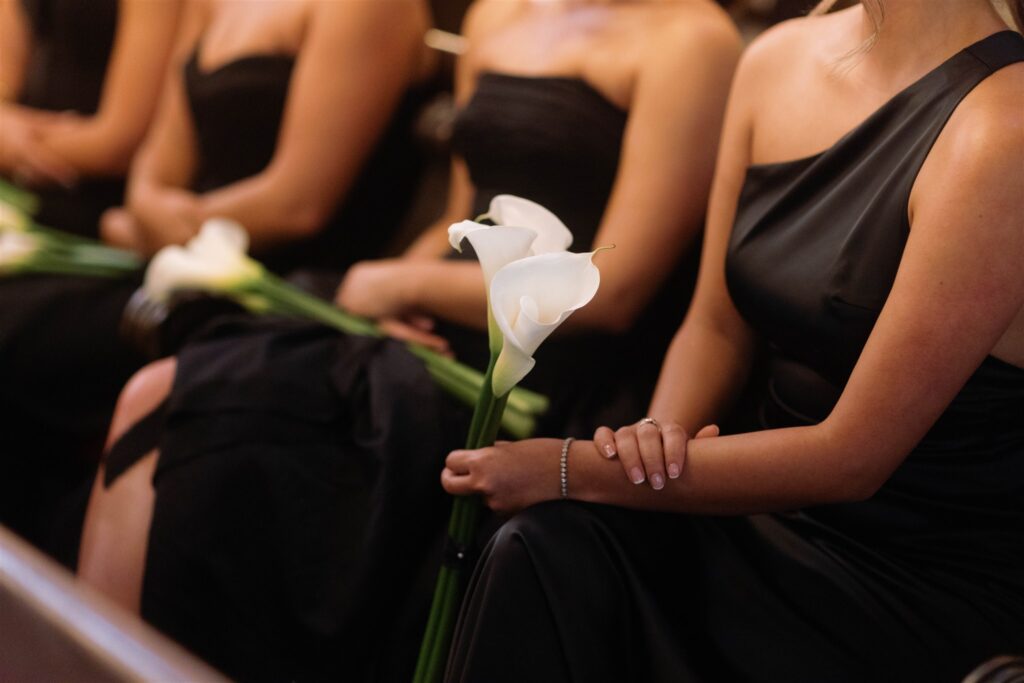 Bridesmaids in black gowns holding calla lilies