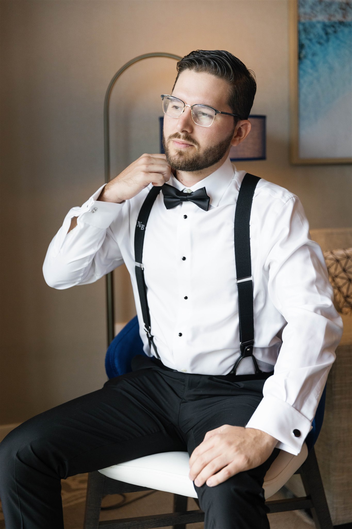 Groom adjusting his bow tie while getting ready at The Loews