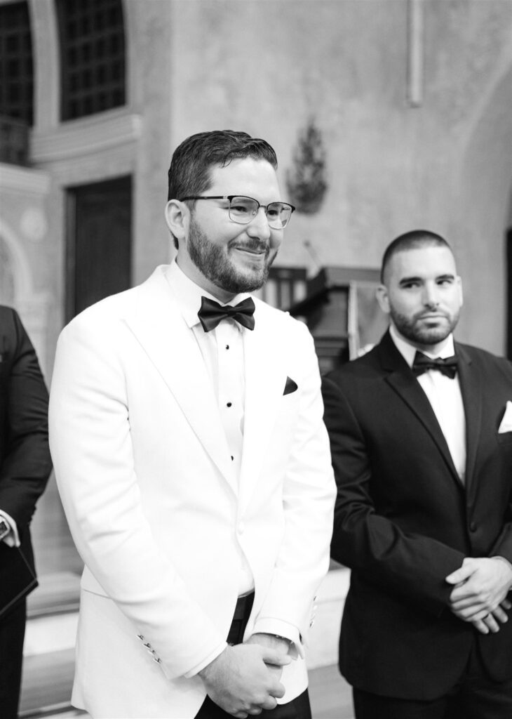 Groom smiling at the altar beside his best man