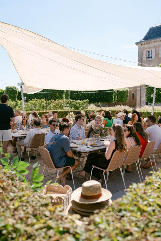 Guests seated at long tables under a canopy for brunch in the orchard garden