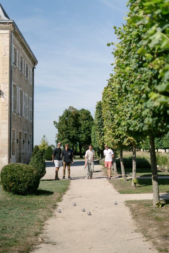 Guests walking along a tree-lined gravel path beside Château de Varennes