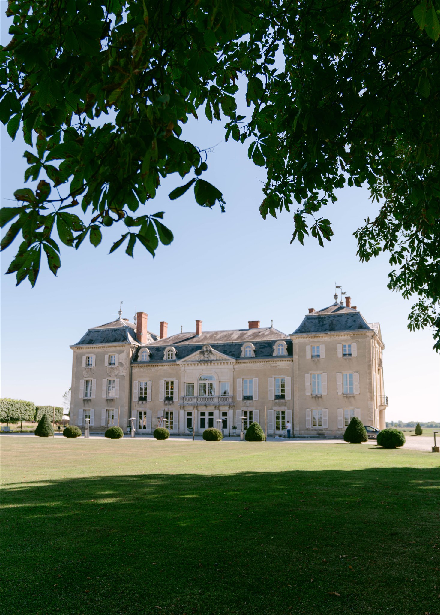 Château de Varennes seen across the lawn through tree branches