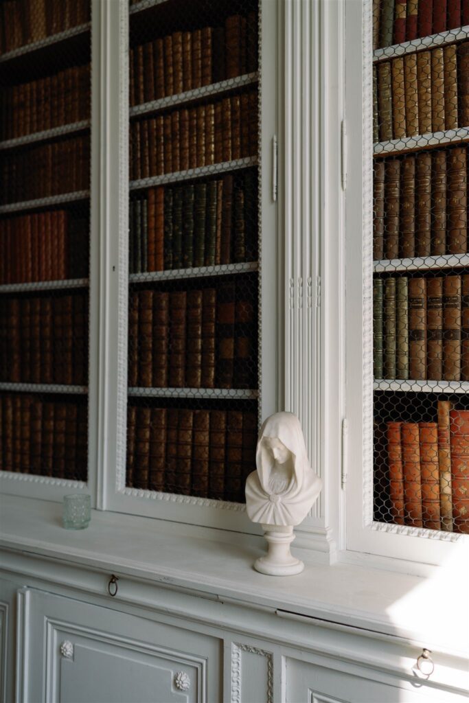 Library shelves filled with leather-bound books inside Château de Varennes