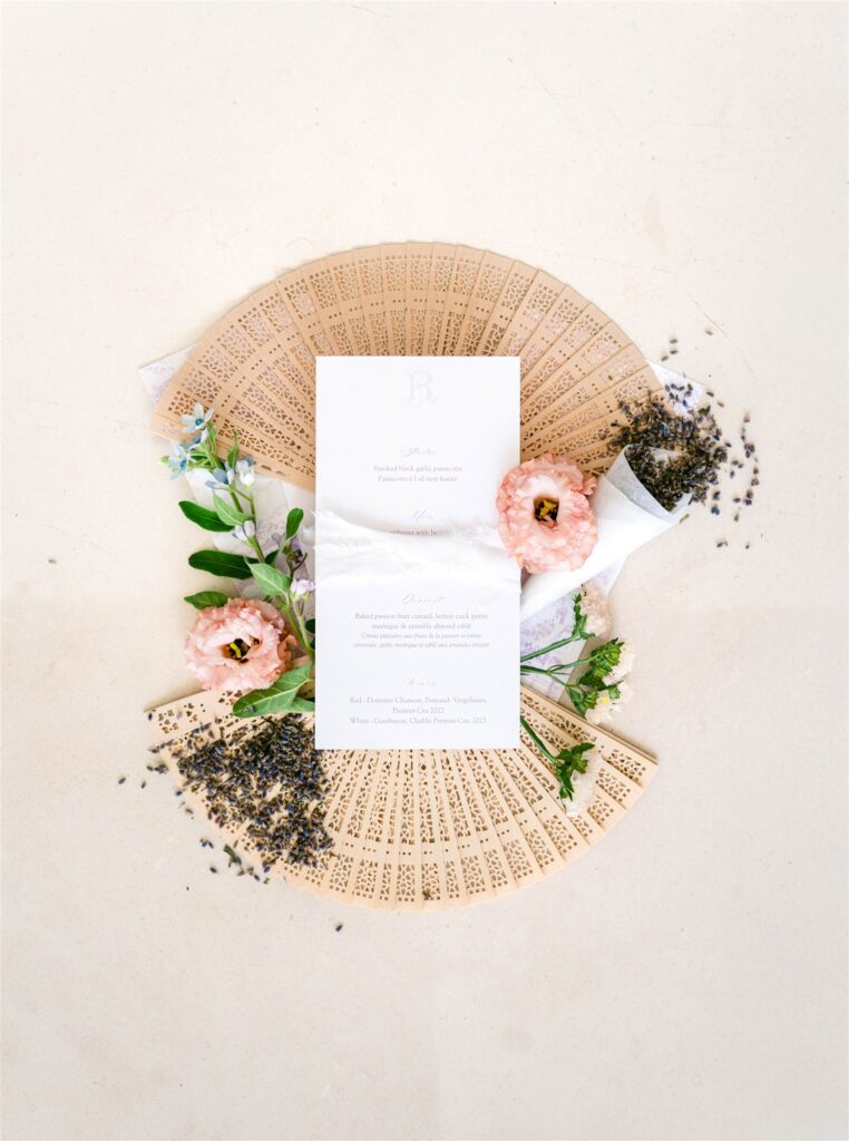 Wedding invitation suite styled with pink flowers on a woven wicker plate