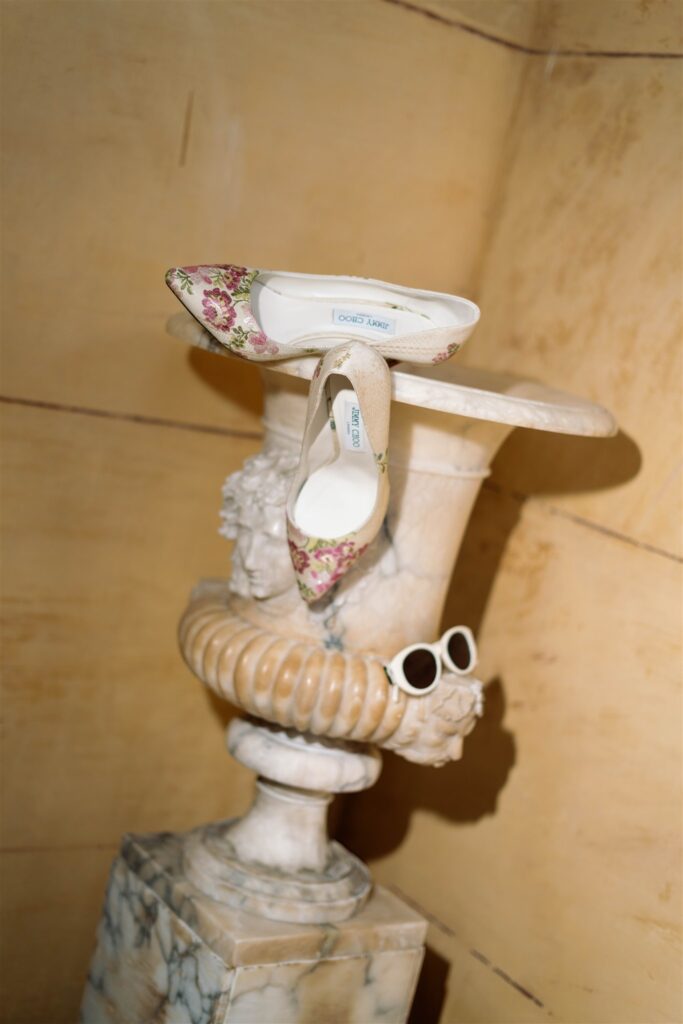 Wedding shoes and sunglasses styled on an antique stone urn