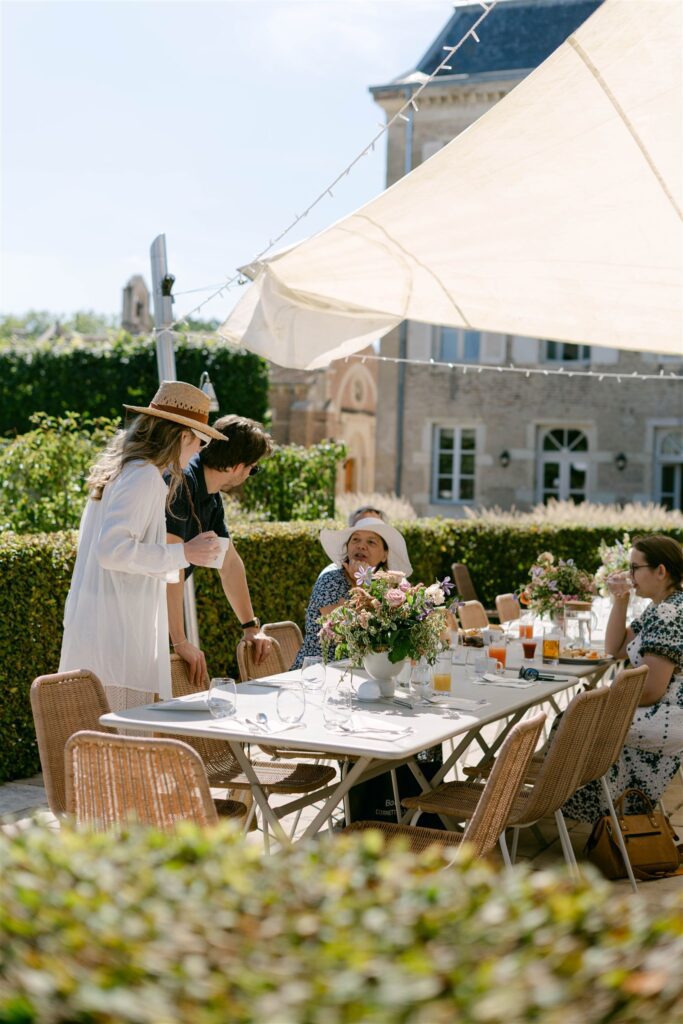 Brunch table set beneath white umbrellas with the château behind