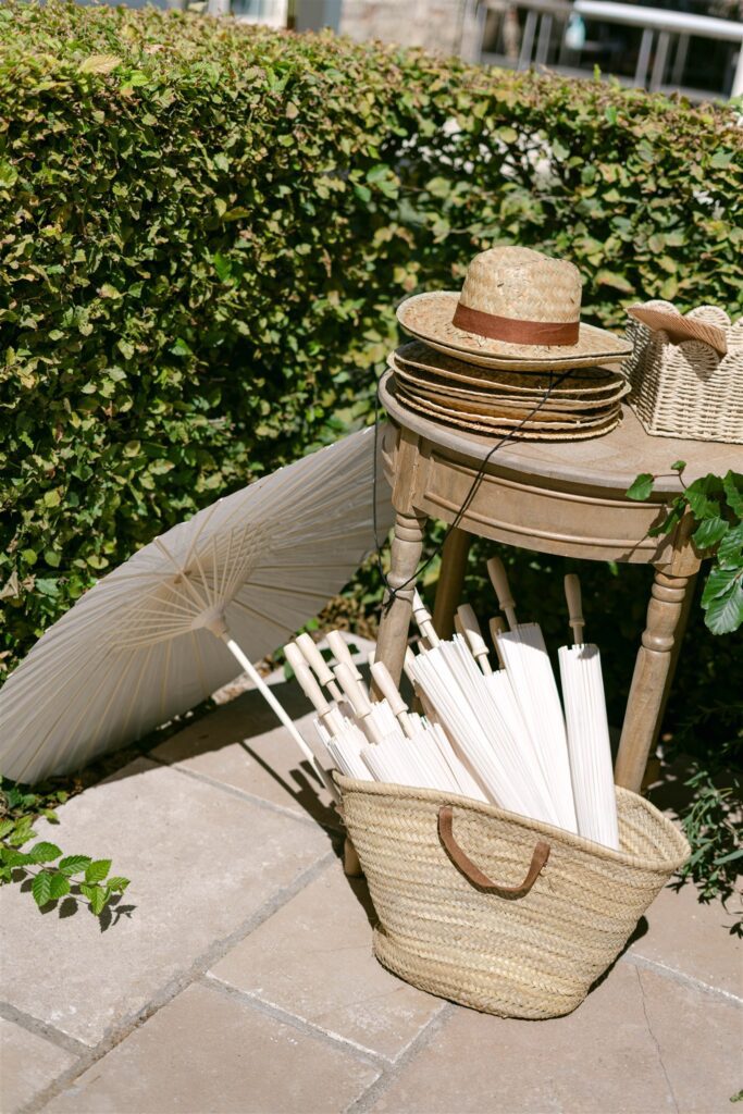 Straw hats, parasols and a basket on a garden chair