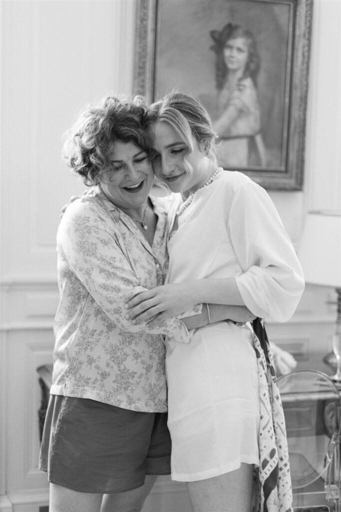 Black and white photo of Romy embracing a loved one in the bridal suite