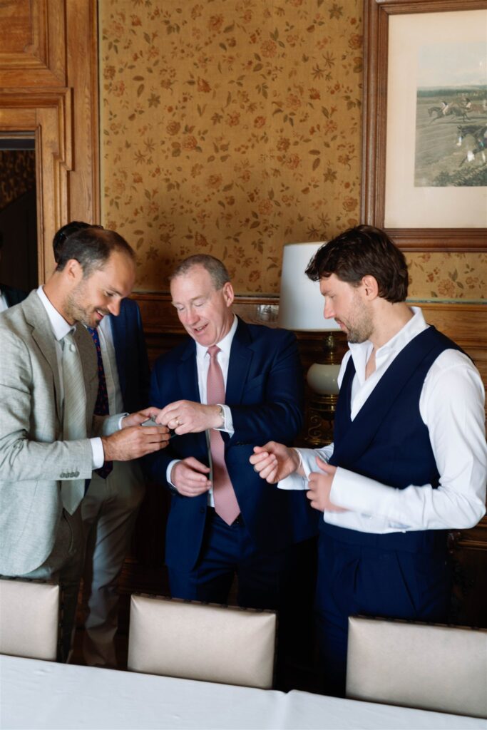 Jonathan getting ready with his groomsmen and family in a wood-paneled room at the château