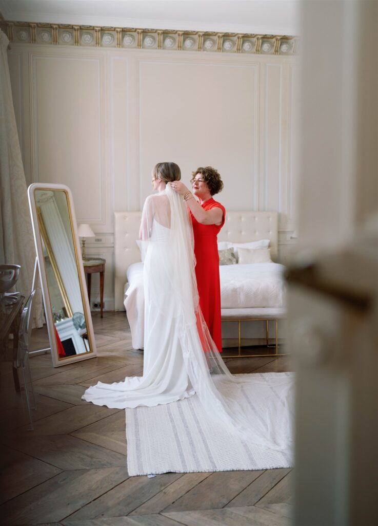 Romy having her wedding dress and veil adjusted in front of a mirror in the bridal suite