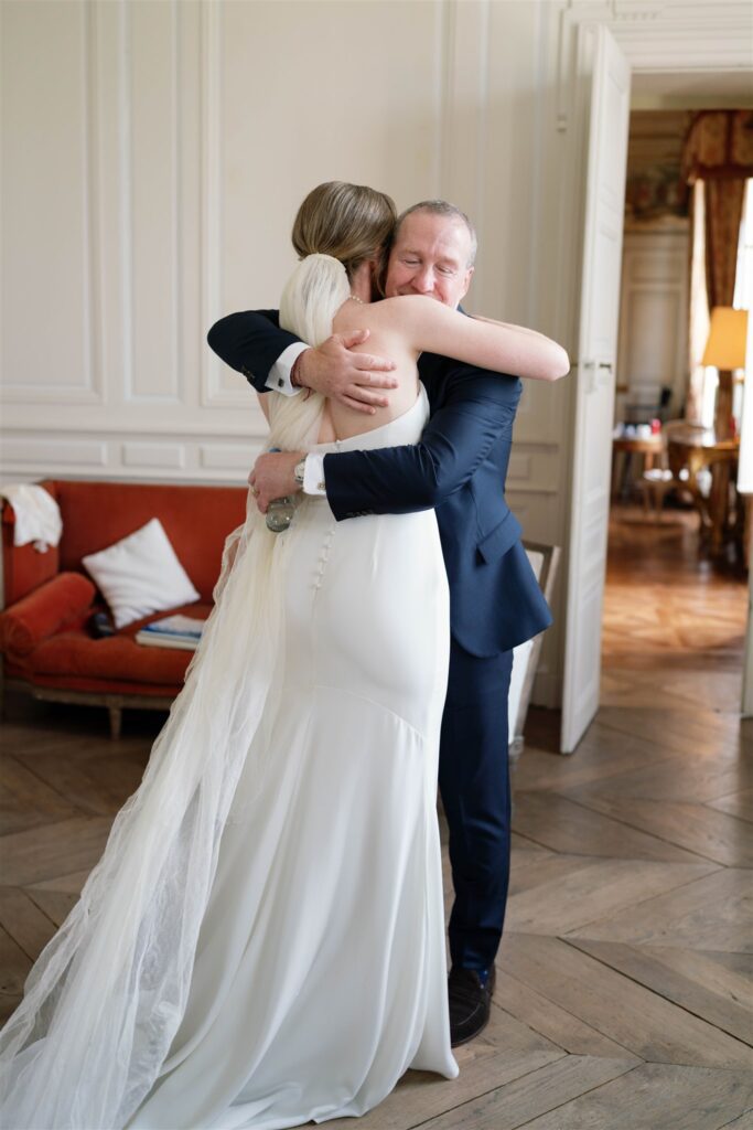 Romy hugging a family member in a navy suit before the ceremony