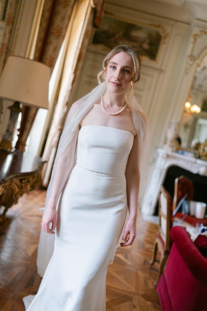 Romy in her wedding gown and veil in a sunlit salon at the château