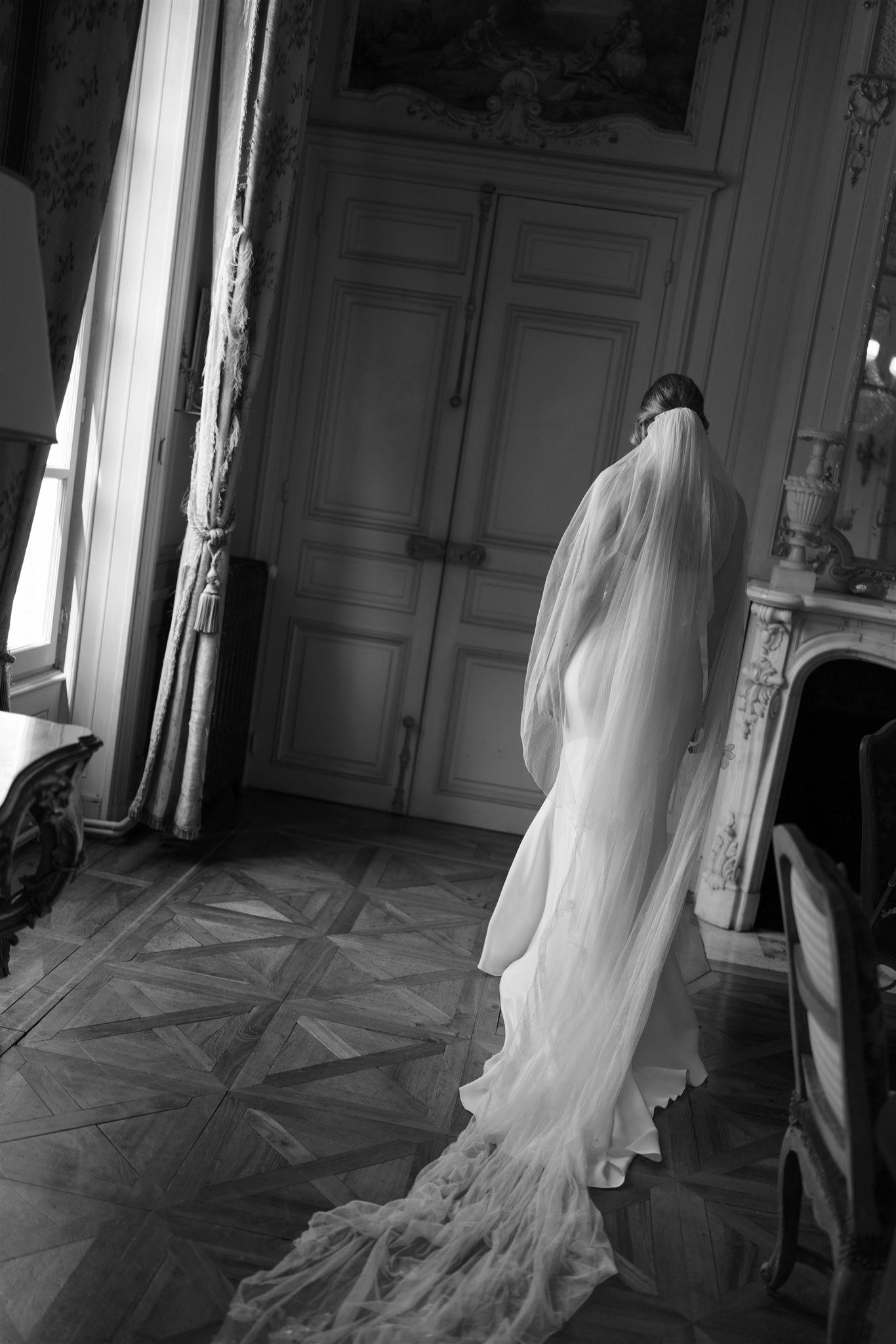 Black and white photo of Romy's long veil trailing across the parquet floor
