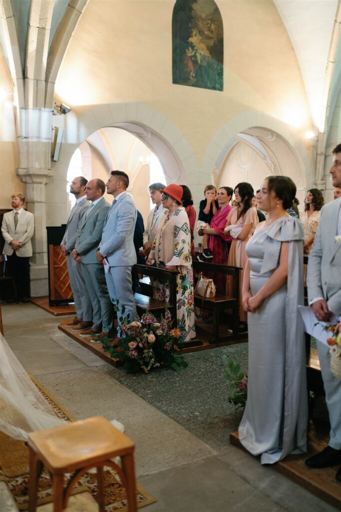Guests in pastel outfits standing in the pews as Romy walks down the aisle