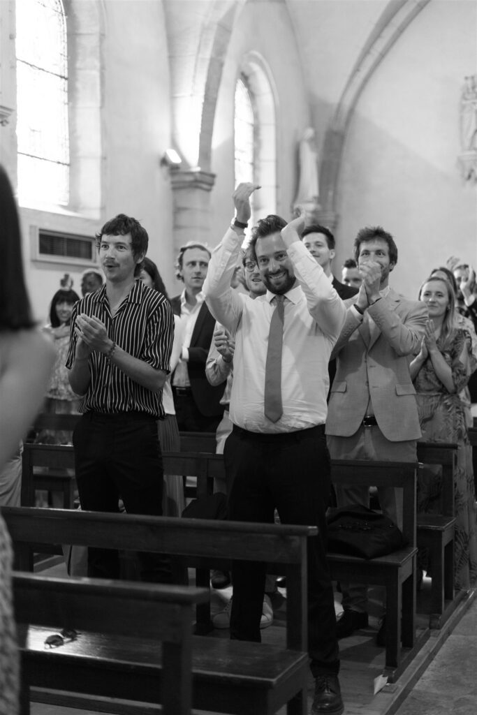 Black and white photo of guests cheering and clapping inside the church