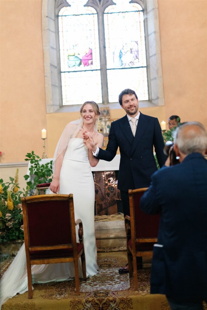Romy and Jonathan facing each other at the altar with guests seated behind