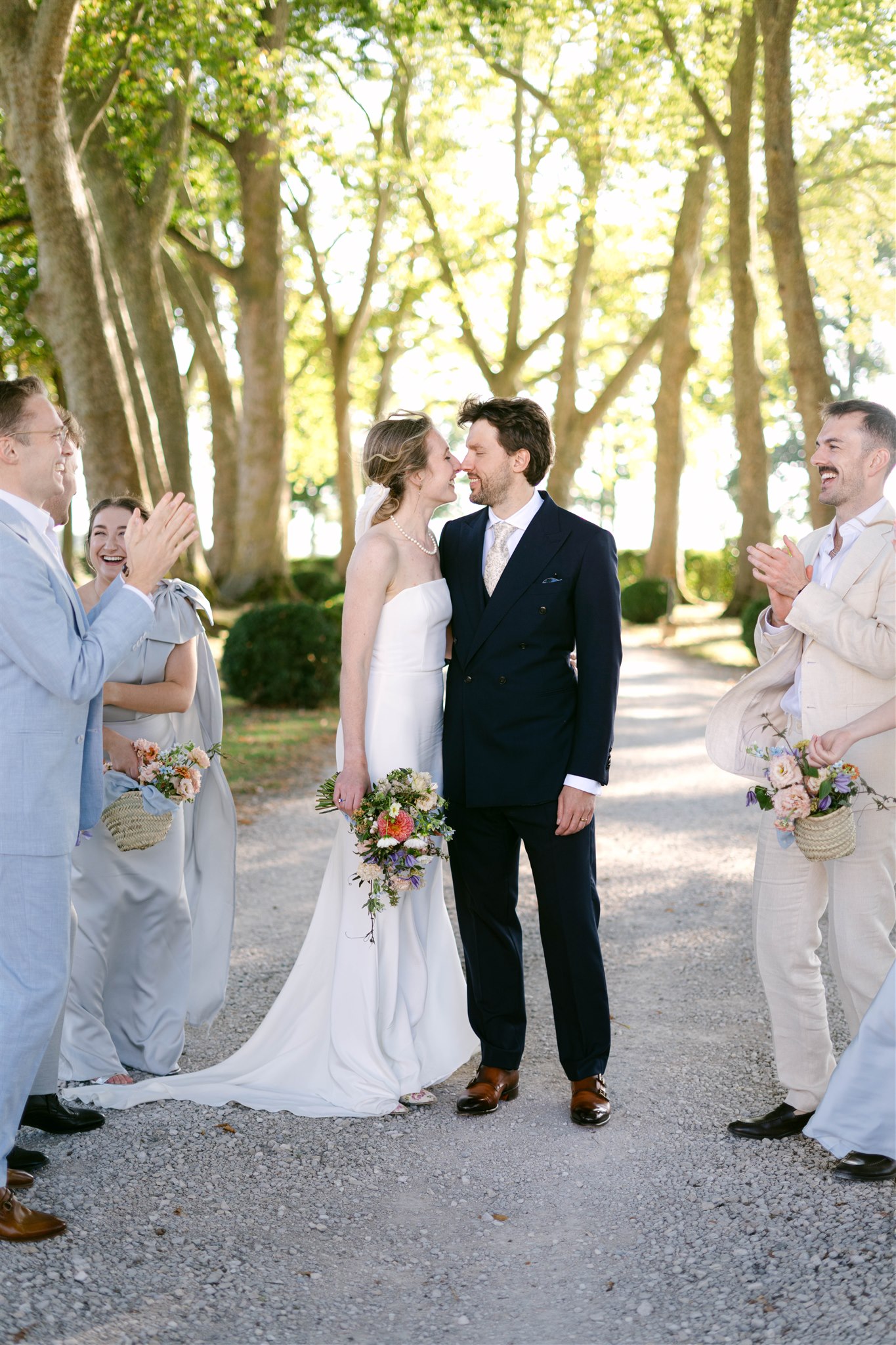 Romy and Jonathan with family and friends gathered on a tree-lined path