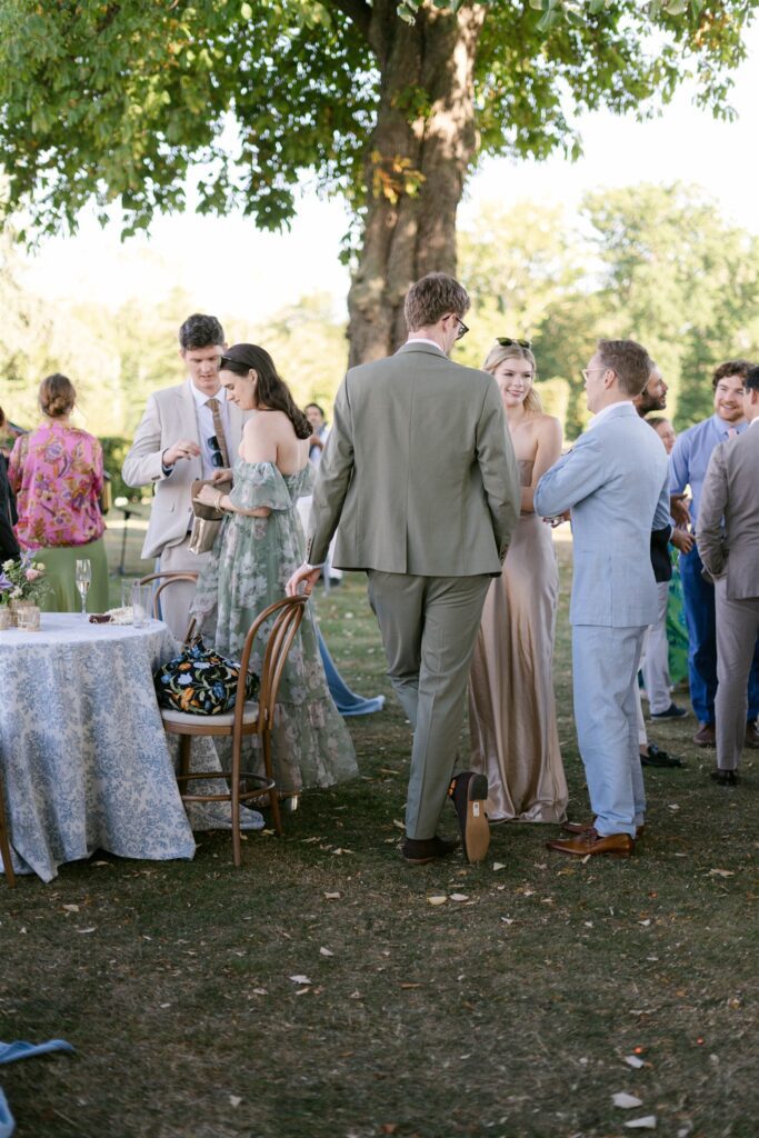 Guests chatting beneath a tree during cocktail hour in the gardens