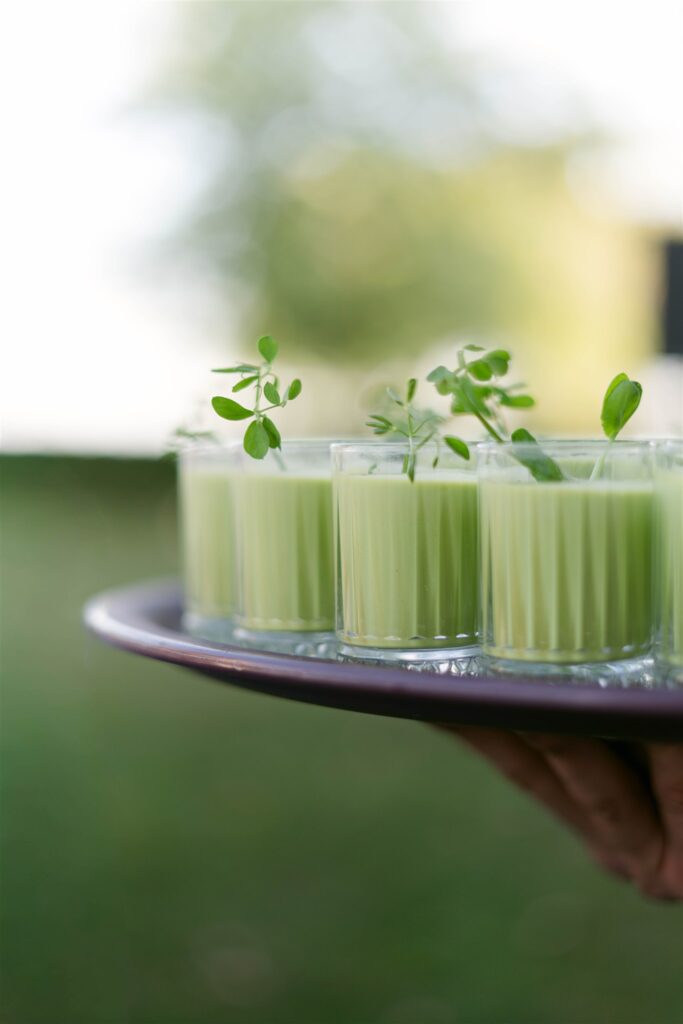 Tray of green gazpacho shooters topped with fresh herbs