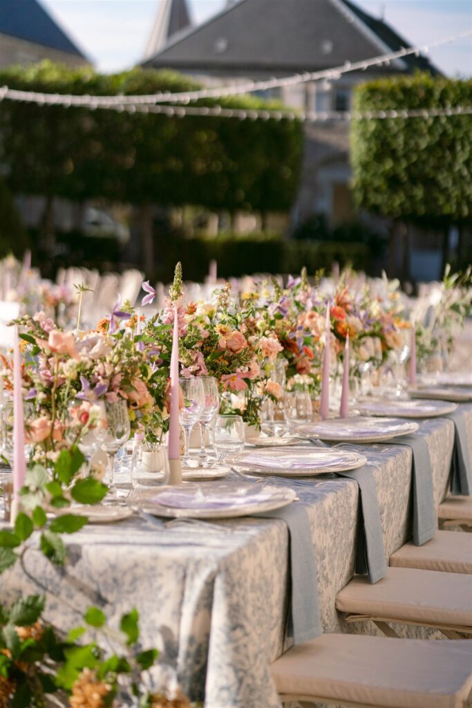 Long reception table decorated with colorful flowers and string lights