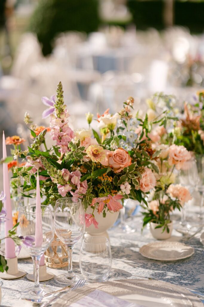 Pink and peach flowers on a reception table beside glassware