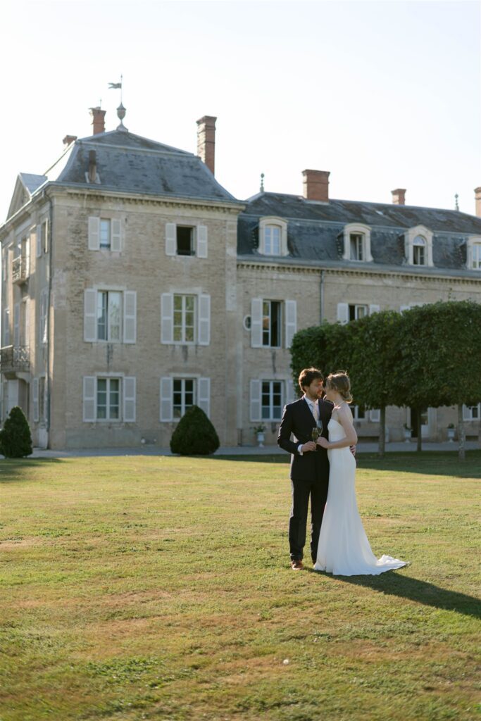 Romy and Jonathan embracing on the lawn in front of Château de Varennes