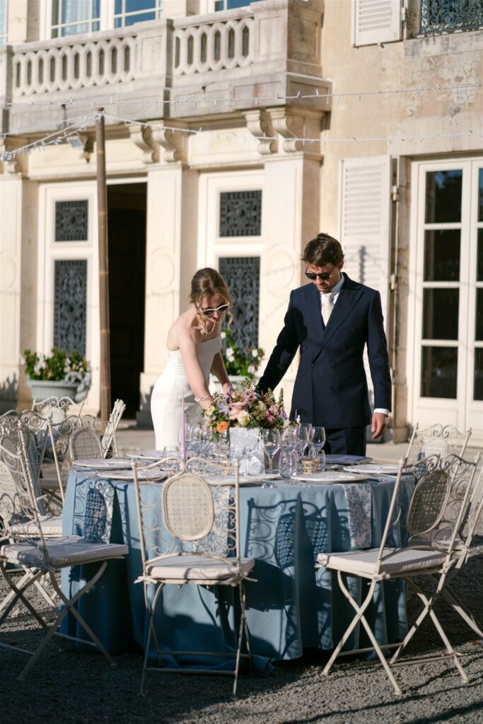 Romy and Jonathan standing by the château terrace doors near a set reception table