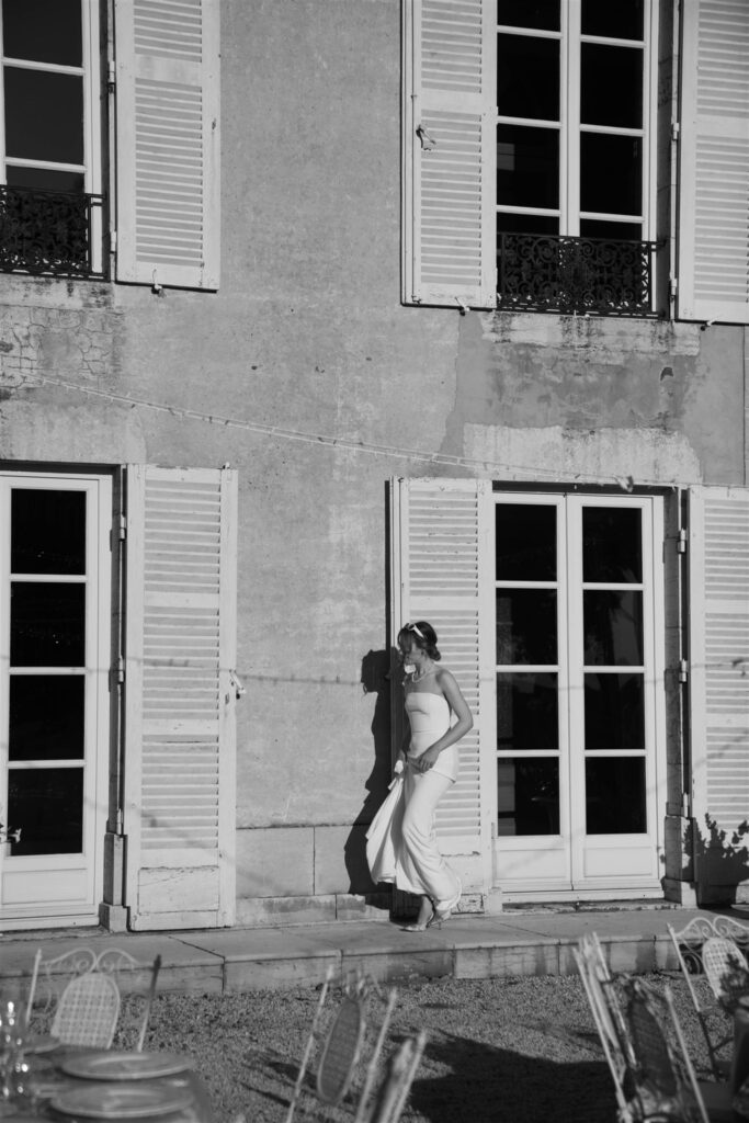 Black and white photo of a guest dancing in front of the château's shuttered windows