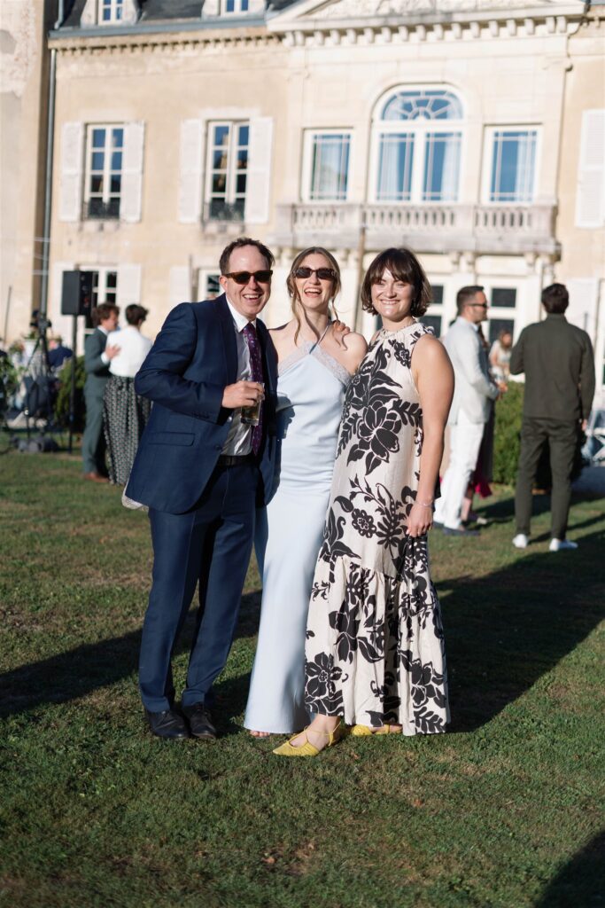 Three guests smiling together on the château lawn
