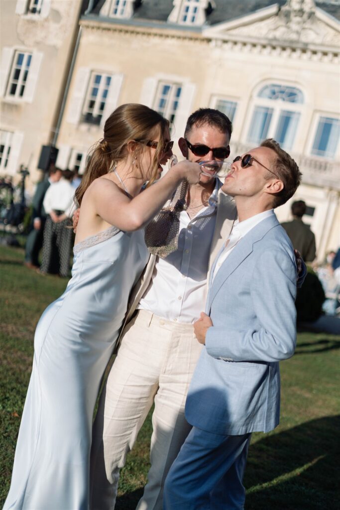 Guests laughing and adjusting sunglasses during cocktail hour in front of the château