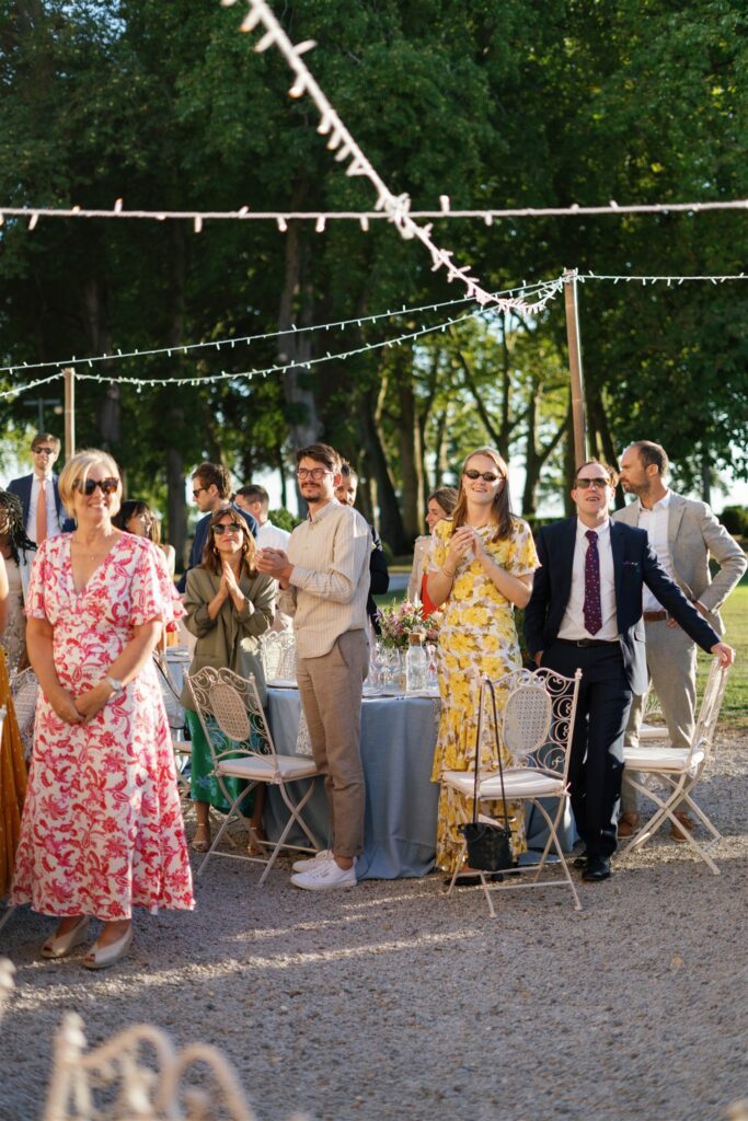 Guests gathered beneath string lights at the reception, a woman in a yellow dress in the center