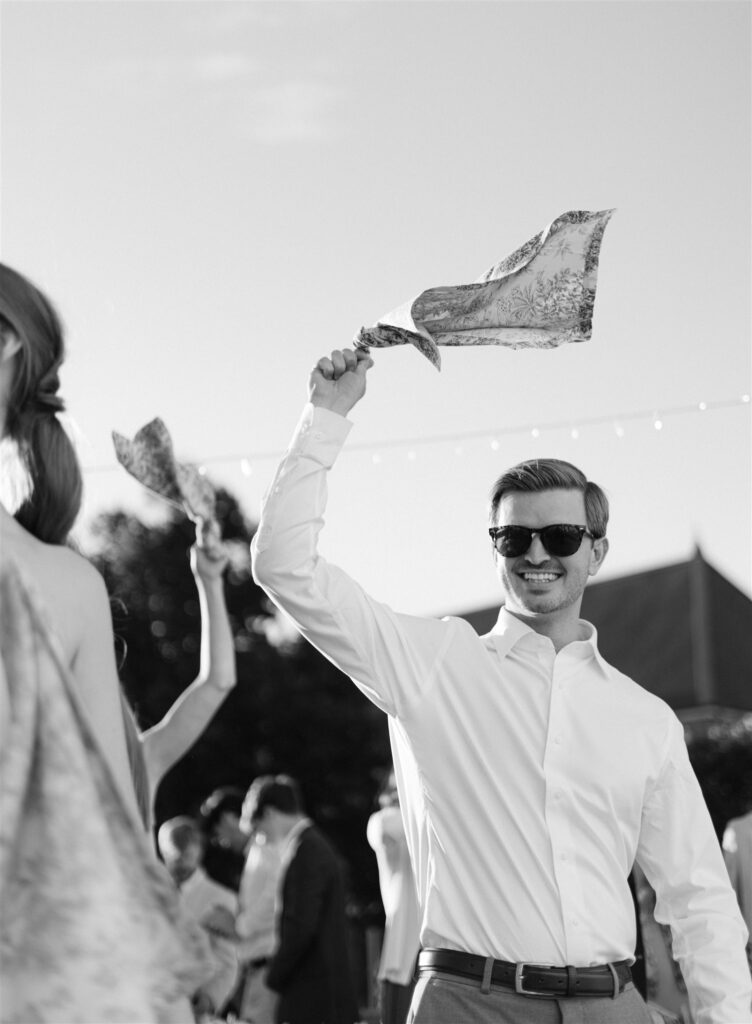 Black and white photo of a guest waving a napkin in the air while cheering