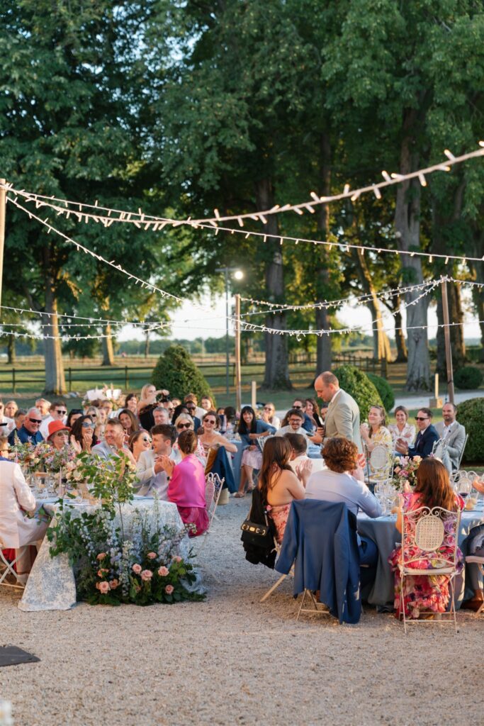 Guests seated at candlelit reception tables beneath string lights