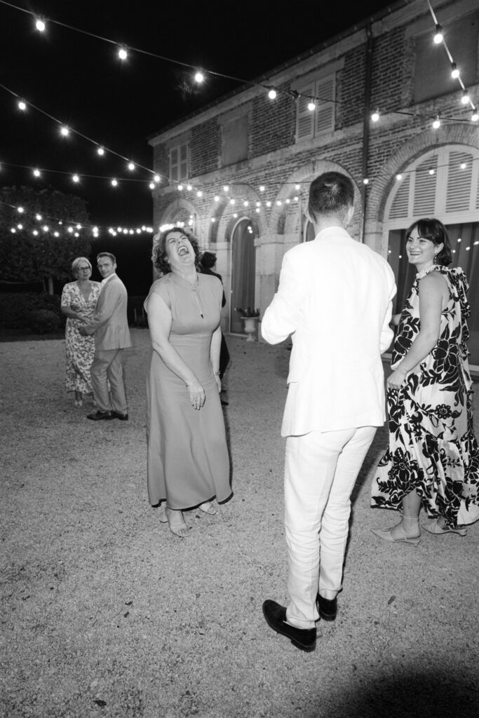 Black and white photo of a man dancing beneath string lights at night