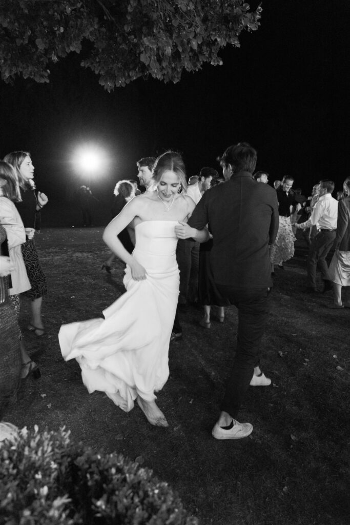 Black and white photo of Romy twirling in her gown on the dance floor at night