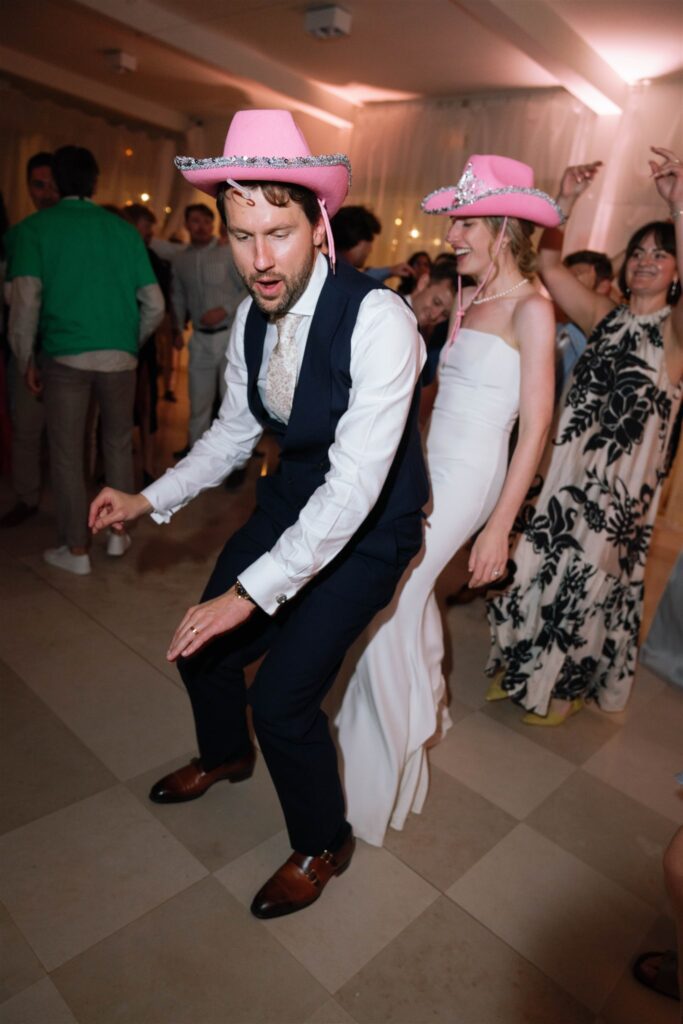 Jonathan dancing in a pink cowboy hat with guests on the dance floor