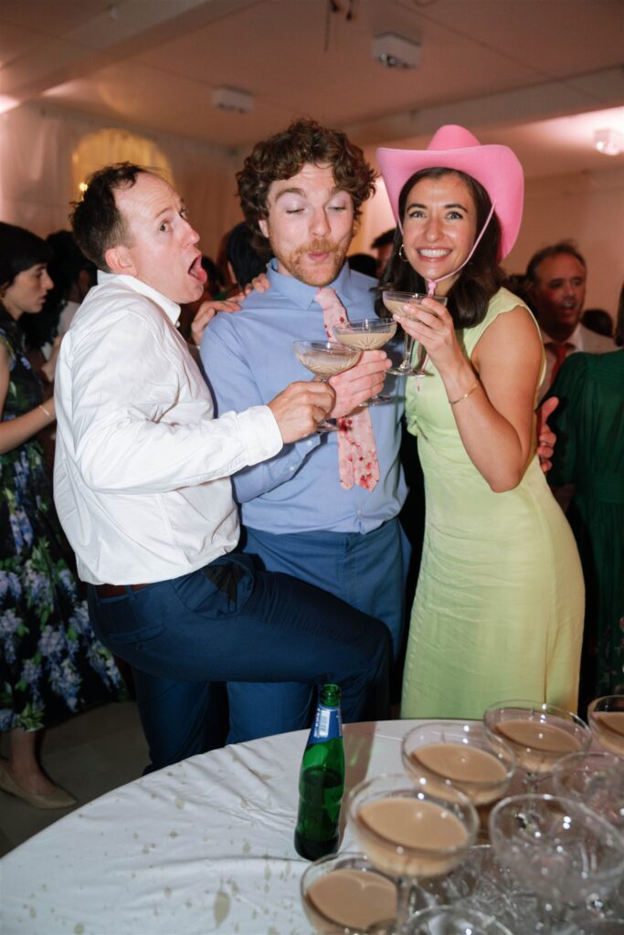 Guests laughing and celebrating on the dance floor, one wearing a pink cowboy hat