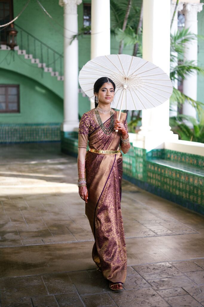 Advaitaa holding a white parasol under the green and white arcade of The Biltmore Hotel