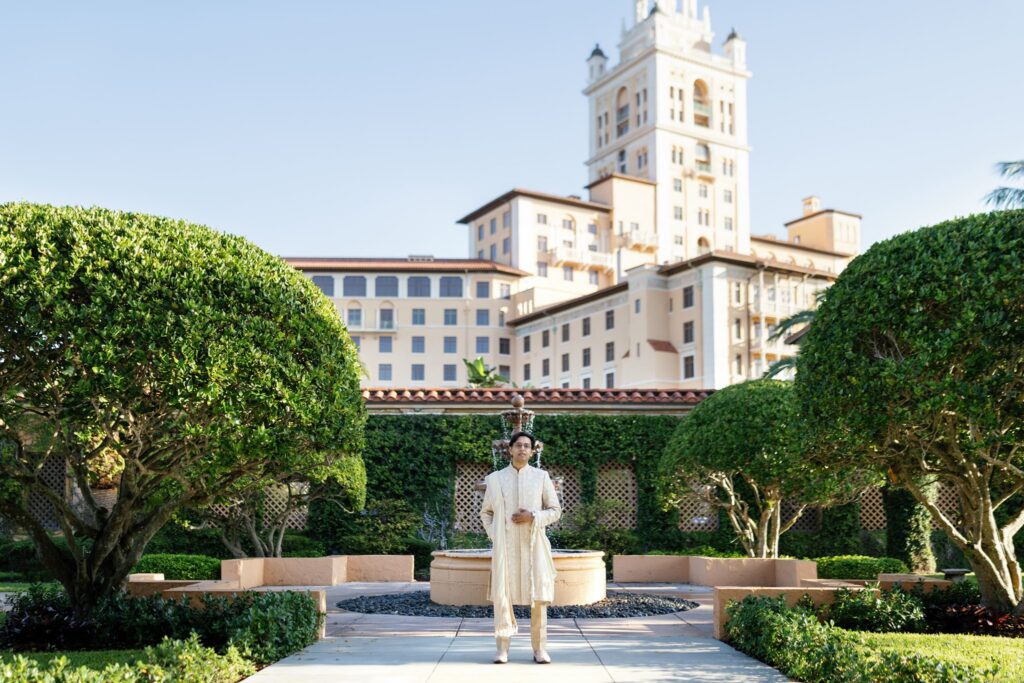 Groom standing in front of The Biltmore Hotel tower in the garden