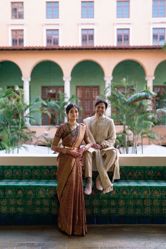 Advaitaa and Tejus seated together on a green tiled bench in the courtyard