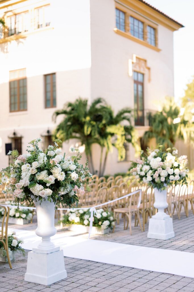 White urns of white flowers lining the ceremony aisle at The Biltmore Hotel